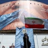 A woman holds an Iranian flag near an anti-U.S. billboard depicting U.S. President Donald Trump and the Strait of Hormuz, in Tehran 