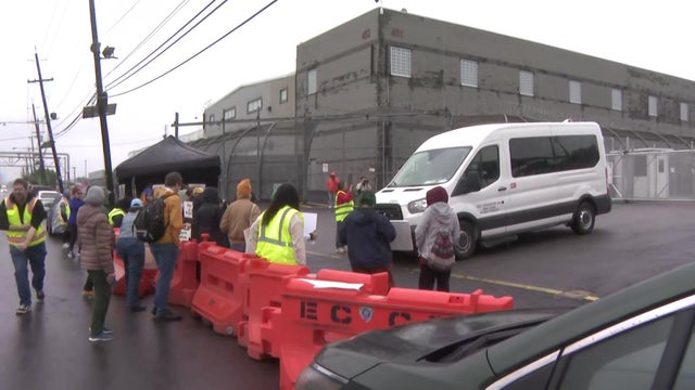 Protesters stand in front of a white van 
