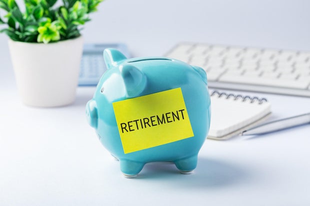 Retirement savings and investment concept with blue piggy bank and office supplies on work table 