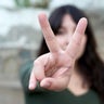 Young woman showing peace sign gesture with hand 
