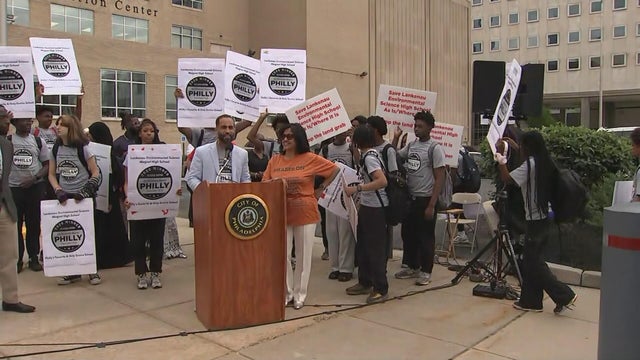 Students and officials hold signs during a rally outside the School District of Philadelphia headquarters 
