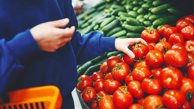 close up of woman's hand with red tomato at the market 
