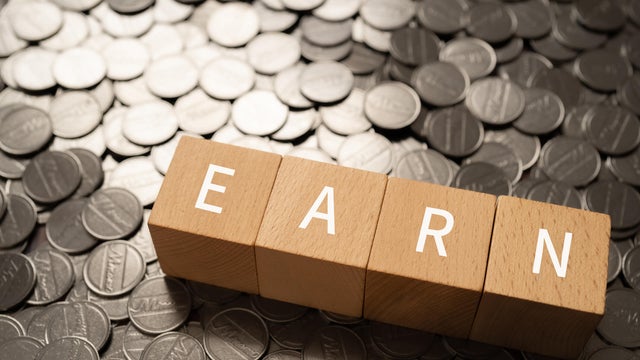 Wooden blocks with "EARN" text of concept and coins. 