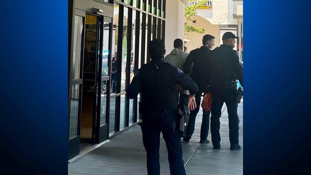 police escorting a man away from a store 
