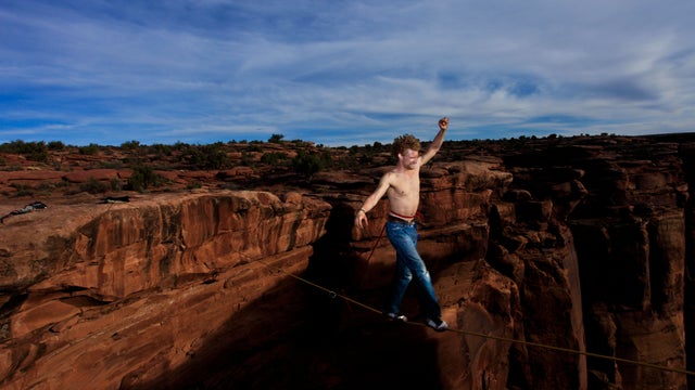 Andy Lewis walks across a highline in a swammy belt at the Fruit Bowl in Moab, Utah, USA. 