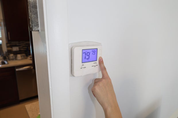 Hand Adjusting Digital Thermostat Temperature Control on Wall