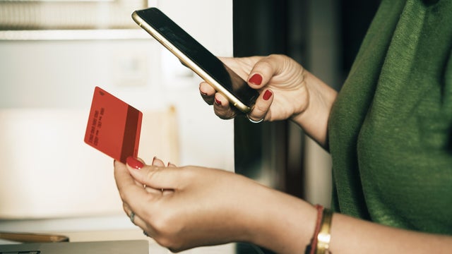 Woman completing an online payment using a mobile phone and bank card 