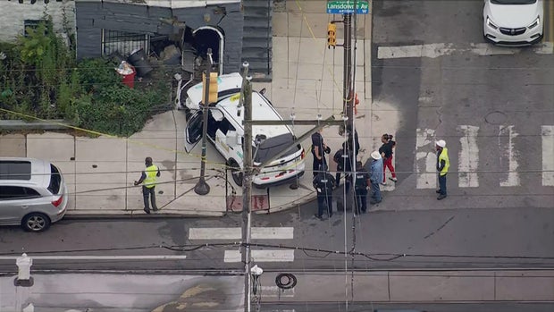 A cab is seen on the sidewalk of an intersection after it crashed into a house 