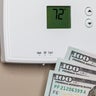 Thermostat for home furnace and air conditioner with cash money. Utility bill savings, energy cost and conservation concept 