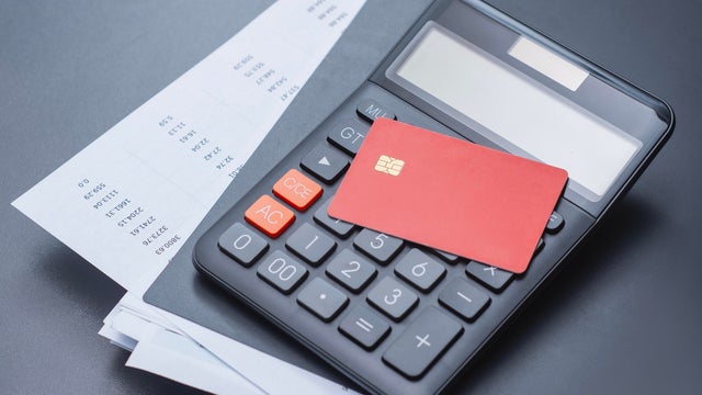 Red credit card with calculator and a payment schedule. Financial concept for credit card usage, loan calculations, monthly payment planning and interest rates. 