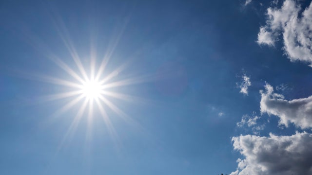 Star-shaped solar corona on a blue sky with few clouds. 