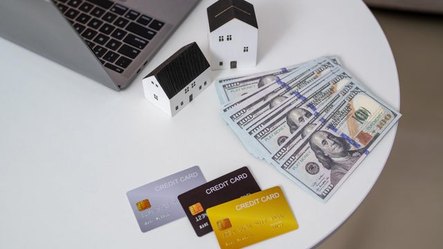 Small house with the dollar bills, credit card and transparent clock background. concept of the home payment interest of house loan monthly installment. Finance and Real Estate Investment. 