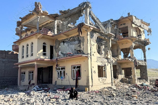 A man sits in front of a destroyed building after an attack, which the Taliban say was an airstrike carried out by Pakistan's security forces, in Samkani District 