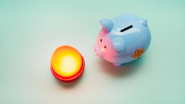 Piggy bank and illuminated lamp on green background, save energy costs 