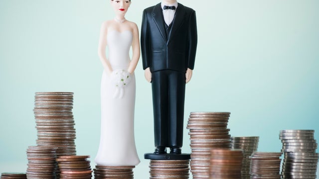Close up of wedding cake figurines on stacks of coins 