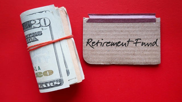 Dollars cash money and paper note with text written RETIREMENT FUND on copy space background - concept of financial planning saving money goal on purpose of retirement security 