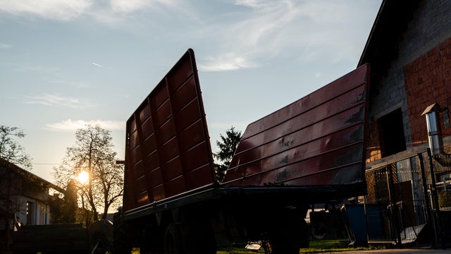 Farm trailer silhouette at sunset in rural yard 