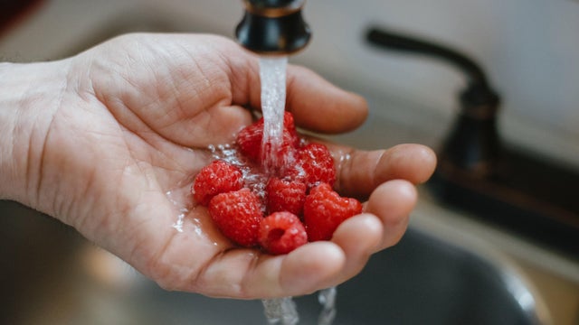 Male Hand Under Running Water to Wash Raspberries 