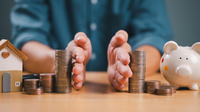 Divorce law and inheritance separation concept. Hand separate saving money, finance, home loan, debt return with piggybank and wood house. Bank business investment. Man separate stack coin on table 