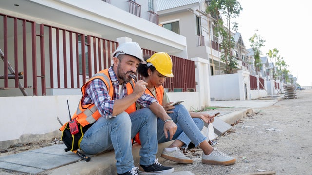 Tired construction worker sitting at construction site. 