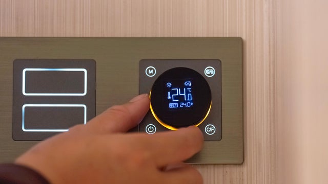 Adjusting digital room thermostat by hand 