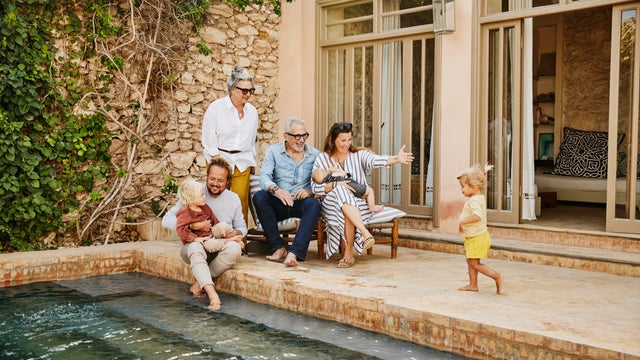 Wide shot smiling multigenerational family relaxing at tropical villa 