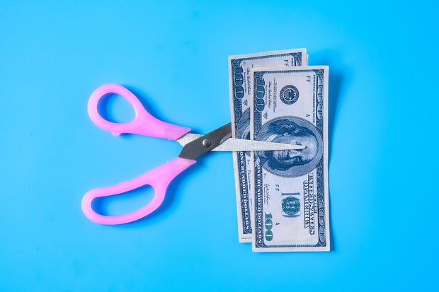 A scissors cutting 100 Dollar bill or bank note.