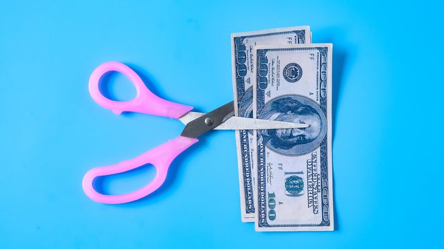 A scissors cutting 100 Dollar bill or bank note. 