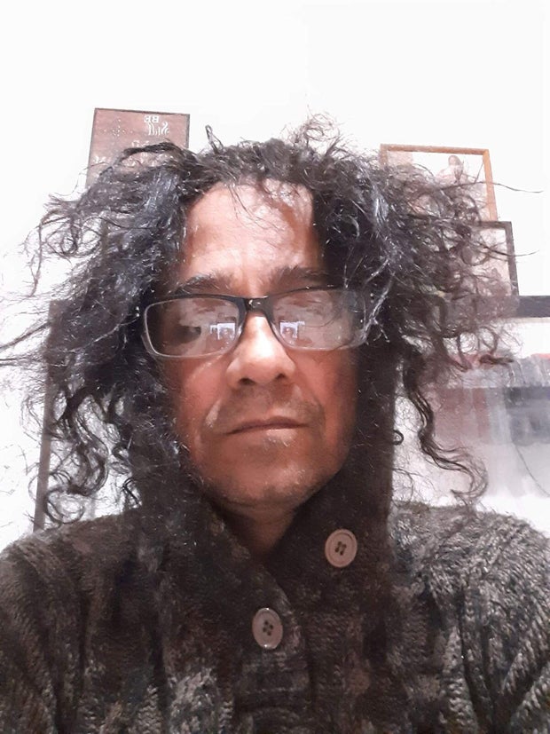 A photo of Rosa wearing glasses with long, frizzy hair sticking out all over his head