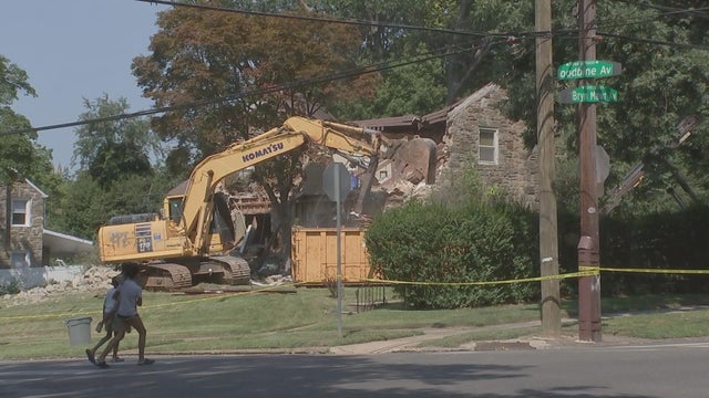 An excavator knocks down a house at Bryn Mawr and Woodbine avenues in West Philadelphia. 