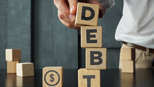 Wooden blocks with the word debt and the image of dollars. Payment of taxes and of debt to the state. Concept of financial crisis and problems. Risk management. Debt exemption 