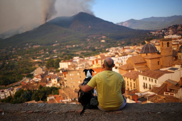 A man and his dog look at a wildfire in a mountain in Onda