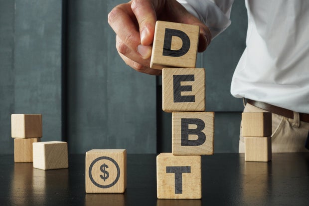 Wooden blocks with the word debt and the image of dollars. Payment of taxes and of debt to the state. Concept of financial crisis and problems. Risk management. Debt exemption 