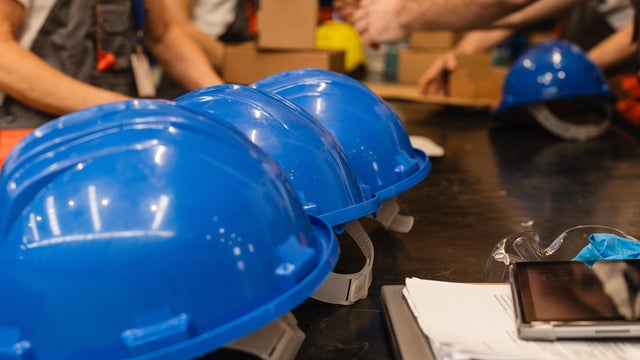 Blue hard hats lined up on table in warehouse or industrial setting 