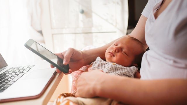 Newborn baby with laptop and smartphone in arms of mother. Muslin and eco-friendly natural materials. Mom with phone. 