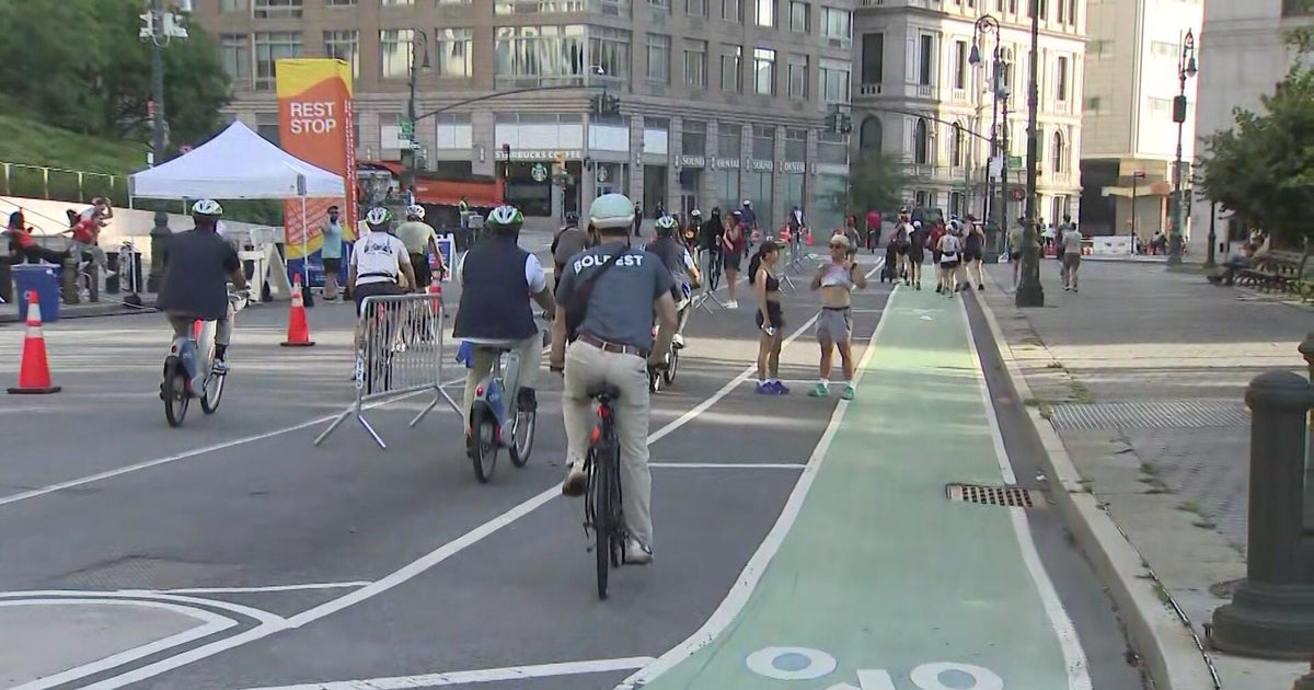 A wide, car-free Manhattan avenue filled with cyclists and pedestrians during the NYC Summer Streets event.