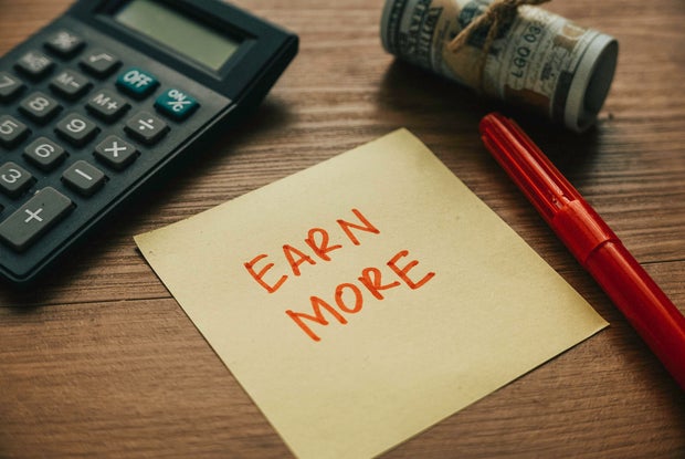 Selective focus of calculator,money pen and paper written with Earn More.