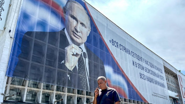 A man walks past a billboard displaying a portrait of Russia's President Vladimir Putin in Sevastopol, on the Russian-annexed peninsula of Crimea, on July 23, 2026. 