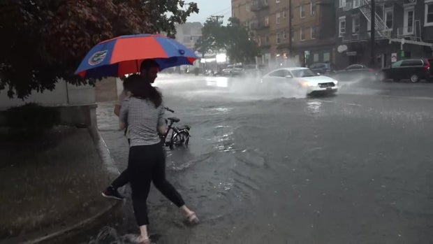 Cars drive through flooded street