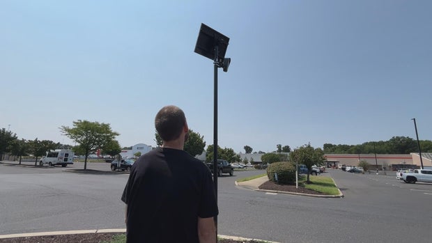 Adam Sheridan looks up at a Flock camera in a South Jersey parking lot 