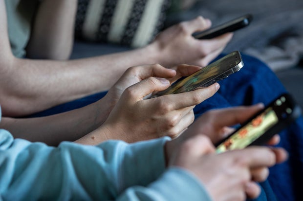 Three teenage boys look at their smartphone screens in the village of St. Jean d'Aulps, France, on April 11, 2026. 
