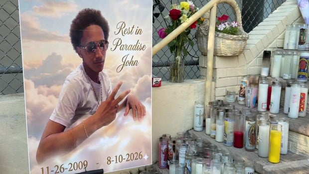 "Rest in Paradise John" poster with prayer candles