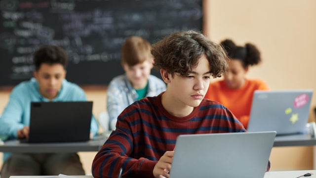 Boy using laptop computer in class during programming lesson 