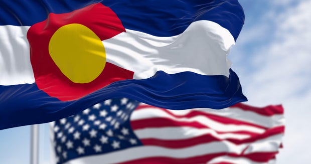 Colorado and US flags waving in the wind on a clear day