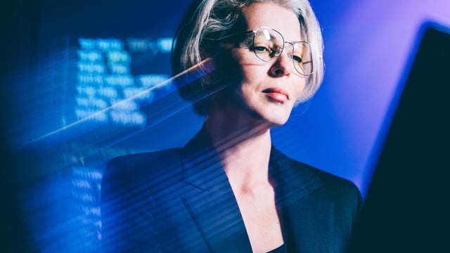 Confident mature businesswoman working with data and AI technology interface 