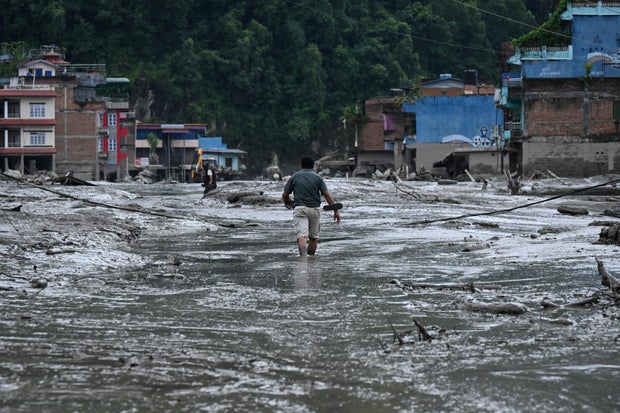 A resident walks along a street covered in mud following flash flooding and a landslide disaster in Devighat, in Nepal's Nuwakot district, on Aug. 26, 2026. 