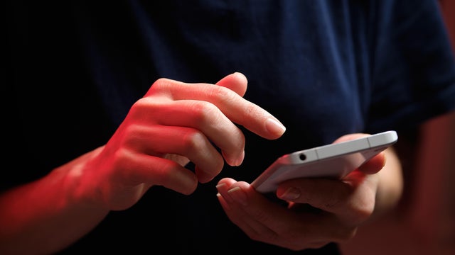 A mobile phone in the hands of a girl. A young woman in a black T-shirt is holding a phone. The fraudster sends an email message. The work of a freelancer, businessman. The wife checks messages and notifications on social networks. Wireless technologies. 