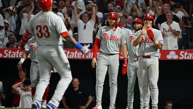 Philadelphia Phillies players wait at the plate for pinch hitter Edmundo Sosa after Sosa hit a grand slam to win the game 