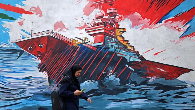 A commuter walks past a mural in Tehran, Iran, Aug. 31, 2026. 