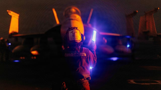 A U.S. sailor signals an F/A-18 Super Hornet on the flight deck of the USS George Washington, Aug. 29, 2026, while the aircraft carrier is deployed in the Middle East. 